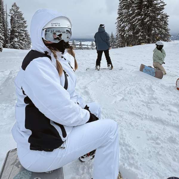 Person in white ski gear sitting on snowy slope, enjoying a winter day outdoors.