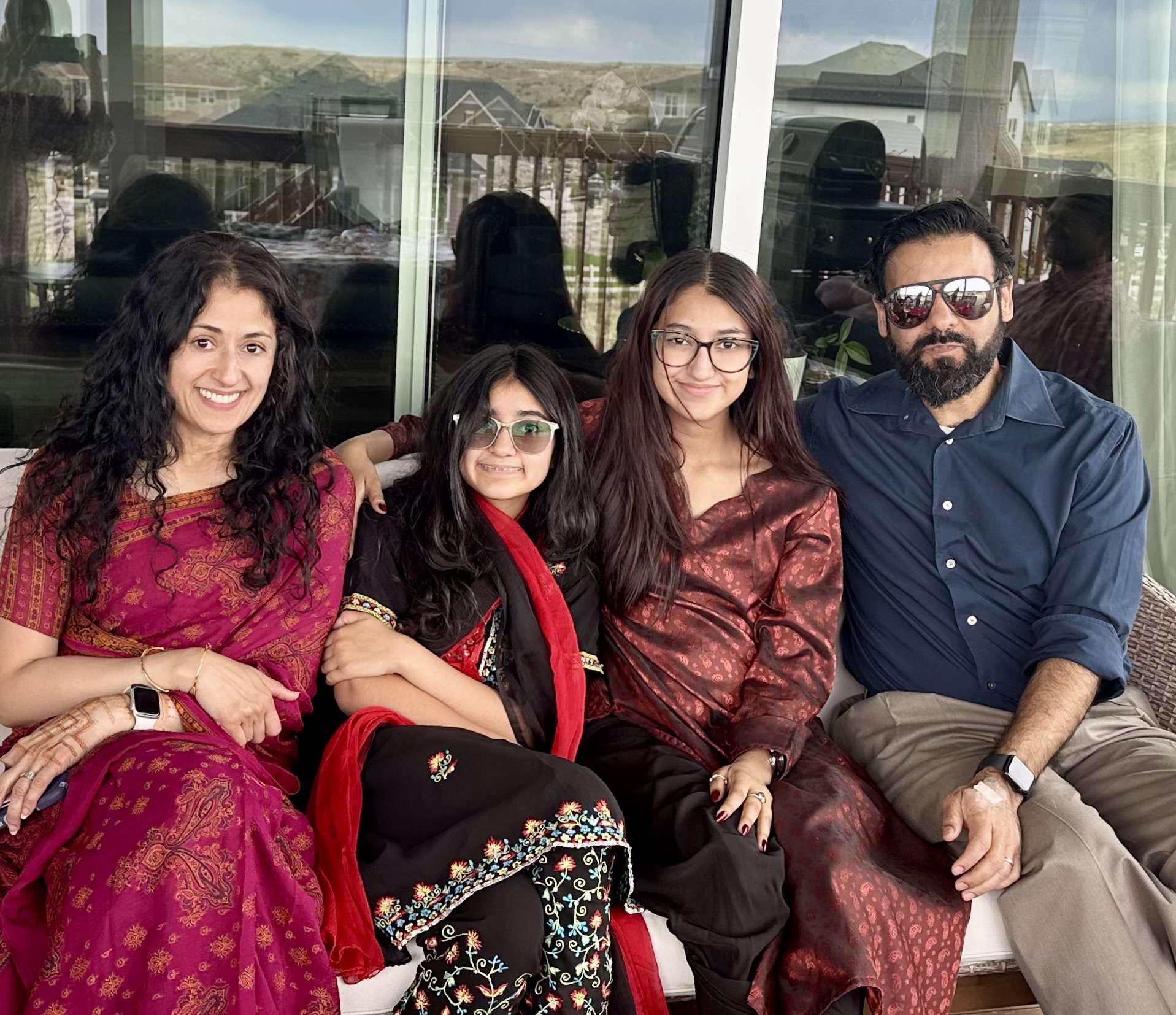 Family smiling together on a couch, dressed in colorful attire.