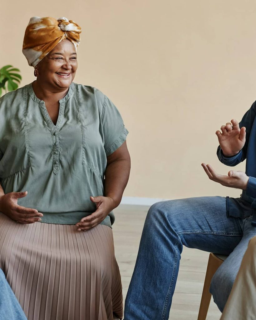 Group of smiling senior people applauding at mental health support group